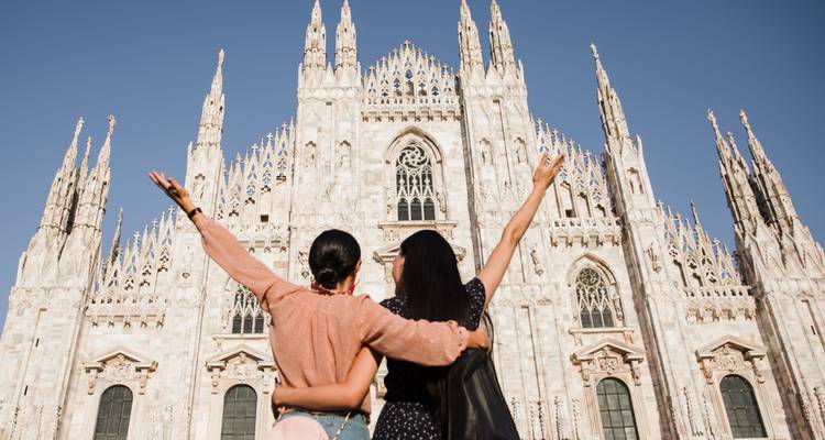 Twee vrouwen met opgeheven armen voor de Kathedraal van Milaan.