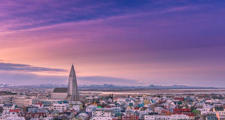 Vista aérea de una ciudad con una gran iglesia y techos coloridos al atardecer.