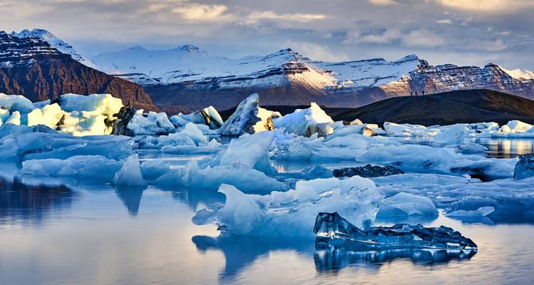 Lagon glaciaire de Jökulsárlón avec icebergs et montagnes au crépuscule.