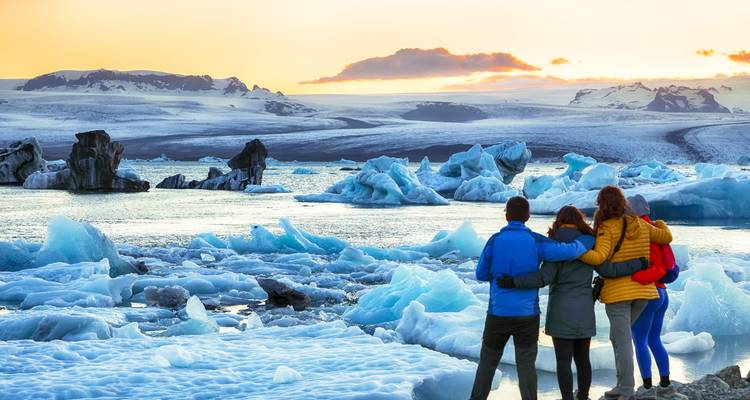Groupe de personnes surplombant le lagon glaciaire de Jökulsárlón au coucher du soleil.
