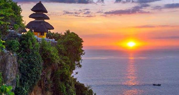 Beautiful sunset view overlooking the ocean with a traditional temple on a cliff.