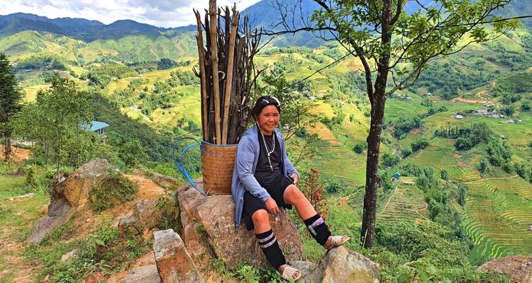 Frau, die auf einem Felsen in einer Berglandschaft sitzt.