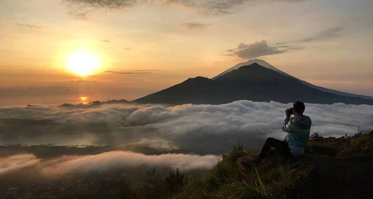 Person, die einen atemberaubenden Sonnenaufgang über einer bergigen Landschaft fotografiert.