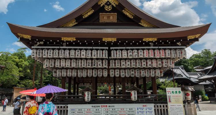 Puerta tradicional de santuario decorada con filas de linternas japonesas bajo un cielo azul de verano.