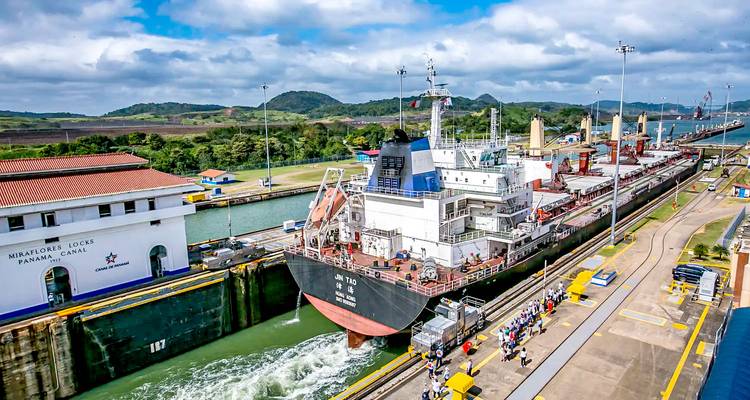 Gran barco pasando por una esclusa de navegación con gente observando.