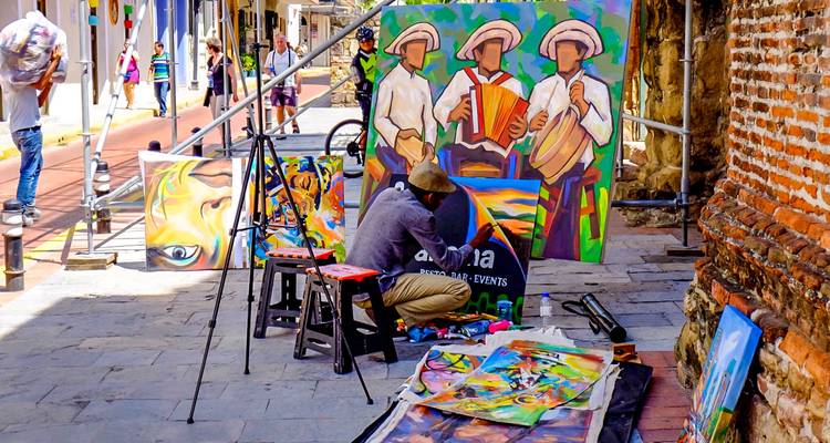 Artista pintando y exhibiendo obras de arte en una calle.