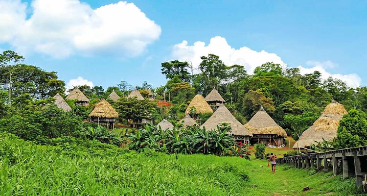 Pueblo con cabañas tradicionales de techo de paja rodeadas de exuberante vegetación.