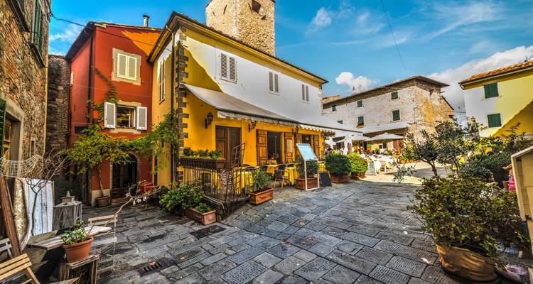 Quaint Italian square with colorful buildings and outdoor seating.