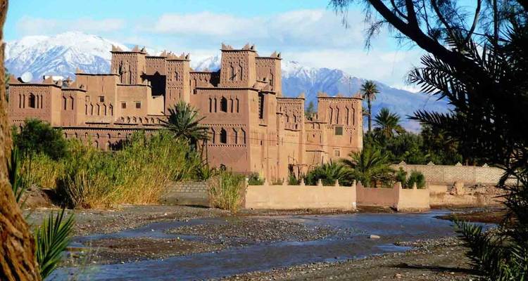 Eine traditionelle marokkanische Kasbah mit Bergen im Hintergrund.