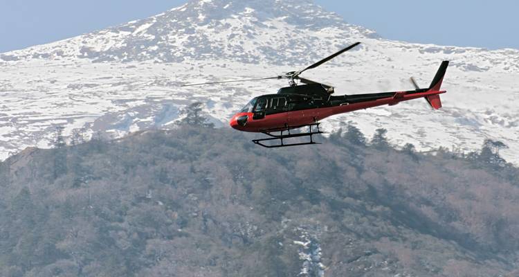 Helicopter flying above snowy mountains.