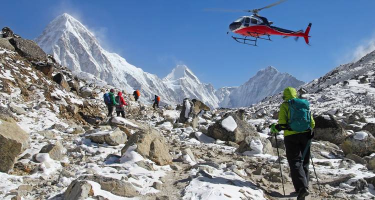 Hikers and helicopter in snowy mountains.