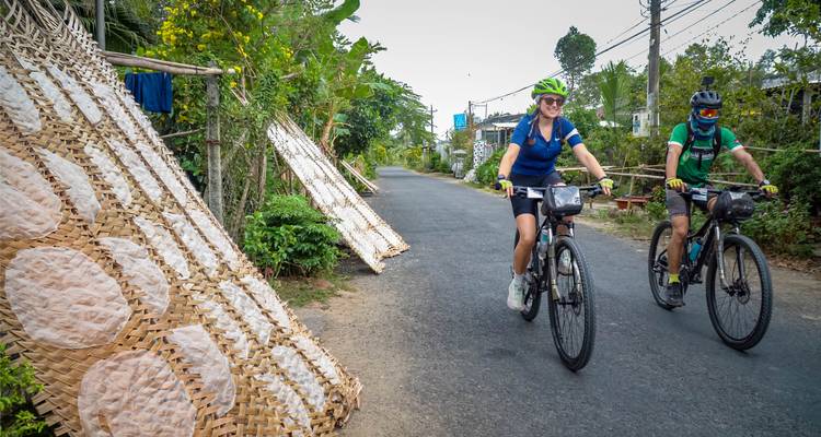 Radfahrer passieren Trockengestelle mit lokalen Erzeugnissen.