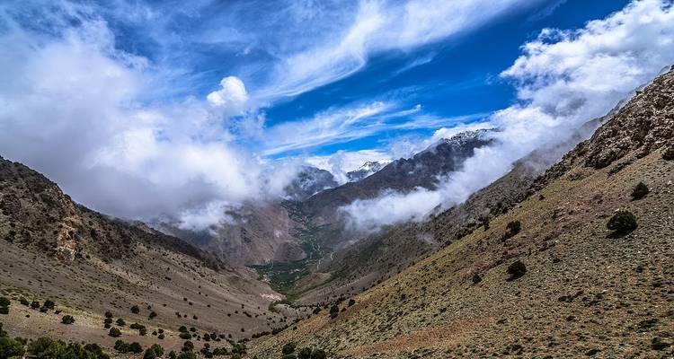 Mountainous landscape with dramatic cloud patterns and deep valleys.