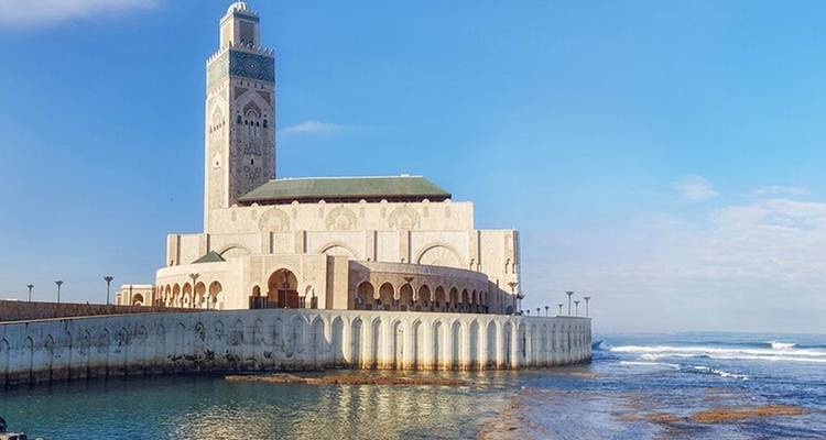 A mosque near the ocean under a blue sky.