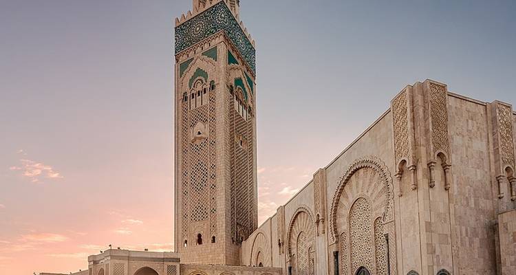 Majestic mosque with minaret against a sunset sky.