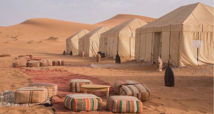 A desert camp with tents and seating.
