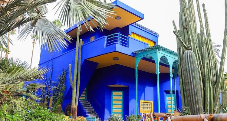 A vibrant blue villa surrounded by greenery.