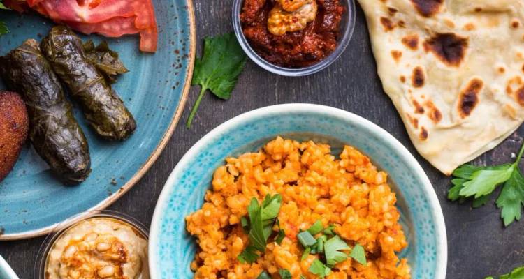 Surtido de mezze turcos que incluye dolma, pilaf de bulgur y salsas sobre una mesa rústica