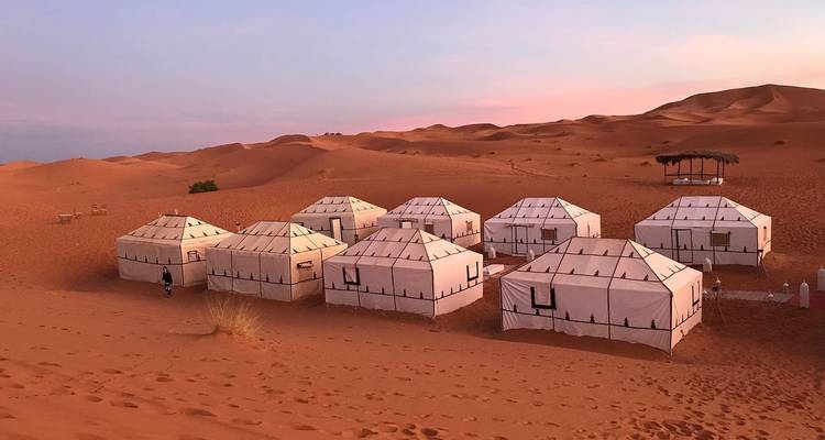 Woestijnkampeerplaats met tenten in een droog landschap.