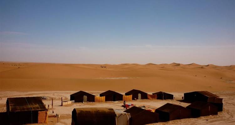 Campement dans le désert avec paysage de dunes.