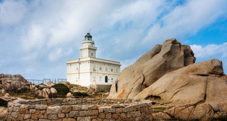 Phare sur un paysage rocheux sous un ciel nuageux.