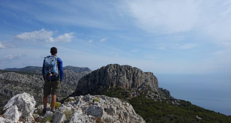 Randonneur avec un sac à dos regardant une colline rocheuse.