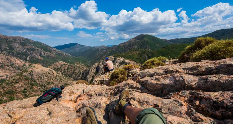 Randonneurs se reposant avec vue sur un paysage montagneux.