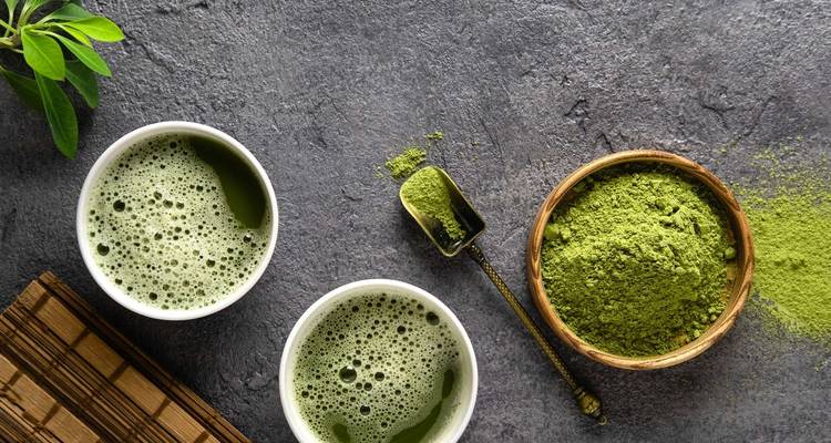 Matcha-Tee und -Pulver ästhetisch auf einem Tisch arrangiert.