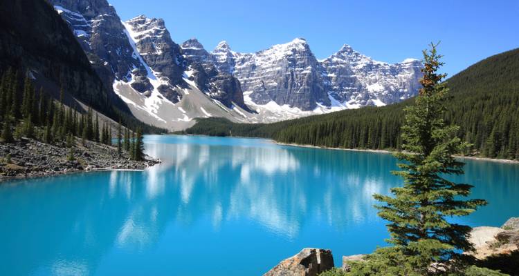 Bright blue lake with surrounding snow-capped mountains.