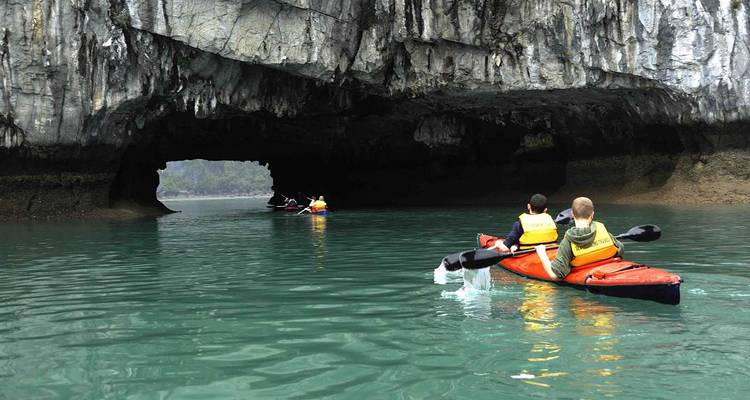 Menschen, die mit dem Kajak durch eine Höhle in der Halong-Bucht fahren.