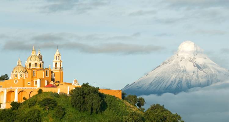 Malerische Bergkirche mit schneebedecktem Popocatépetl-Vulkan, der sich im sanften Licht dahinter erhebt.