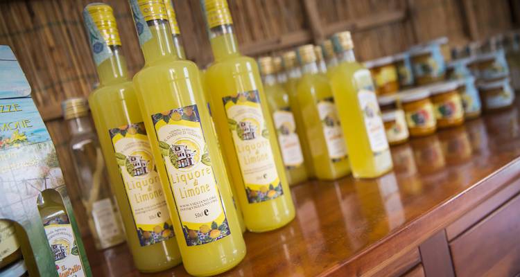 Flaschen mit leuchtendem gelbem Limoncello ordnungsgemäss auf einer Holztheke in einem Hofgeschäft angeordnet.