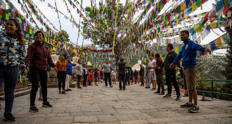 Los visitantes se paran entre innumerables banderas de oración creando un dosel vibrante en la colina de Swayambhunath.