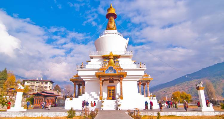 White stupa with gold decorations and people around.