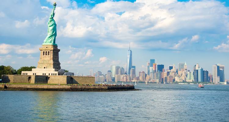 Statue of Liberty standing proudly on Liberty Island with the Manhattan skyline across the Hudson River.