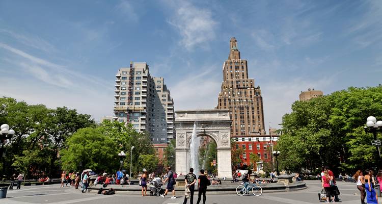 Washington Square Park animé de visiteurs autour de l'arche en marbre et des bâtiments de la ville par une belle journée ensoleillée.
