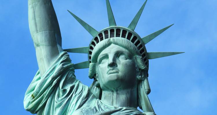 Vue rapprochée de la Statue de la Liberté sur un ciel bleu dégagé.