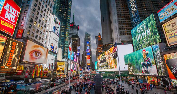 Des panneaux publicitaires lumineux et des foules animées remplissent une célèbre place urbaine illuminée par des néons.