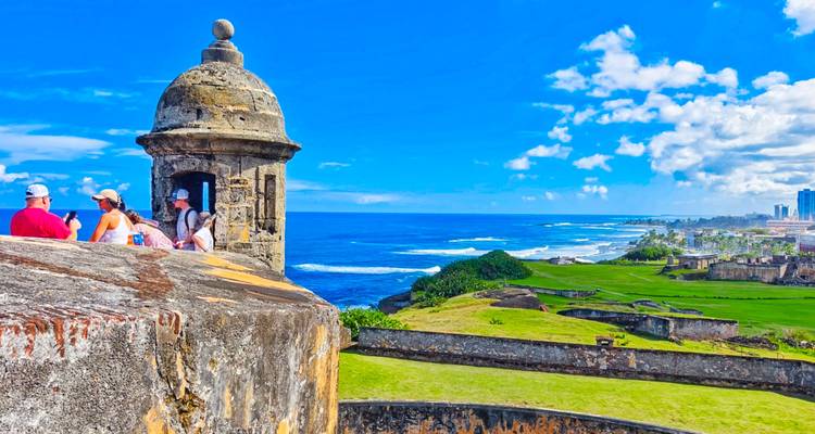 Fortaleza histórica con vista al océano donde las personas disfrutan del paisaje.