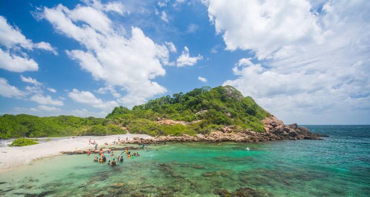 Les plongeurs en apnée apprécient les eaux turquoise cristallines autour d'une petite île tropicale à la végétation luxuriante.