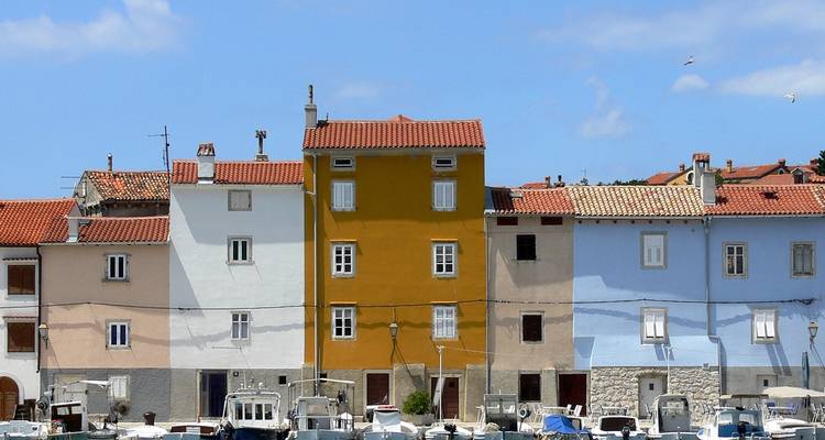 Bunte Häuser entlang einer Uferpromenade mit vertäuten Booten.