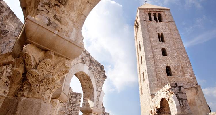 Steinturm und Ruinen unter blauem Himmel.