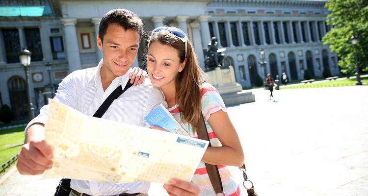 Two people looking at a map in front of a large building.