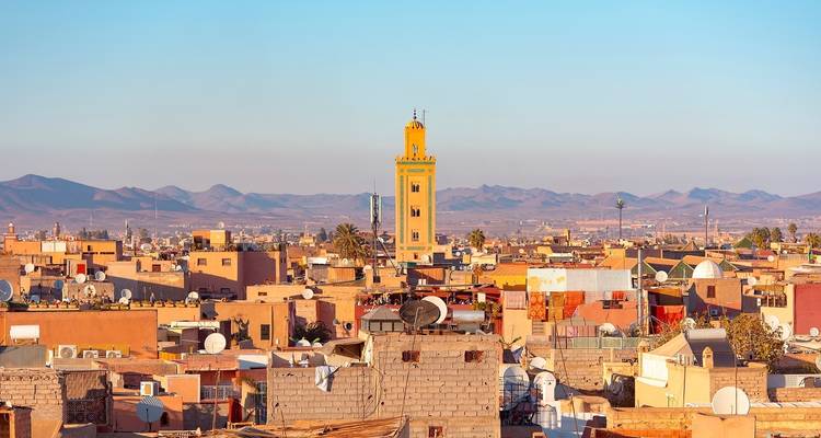 Cityscape with minaret during daytime, showcasing surrounding mountains.