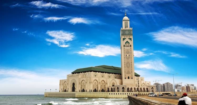 Hassan II Mosque on the coastline under a bright blue sky.