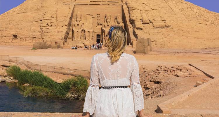 Frau im weißen Kleid vor antikem Tempel, der in einen Felsen gehauen ist