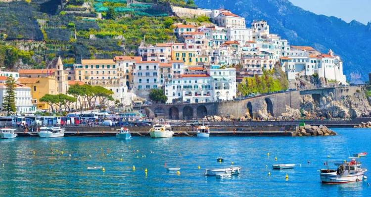 Ville colorée au flanc des falaises le long de la côte d'Amalfi avec des bateaux flottant sur une eau bleu scintillant