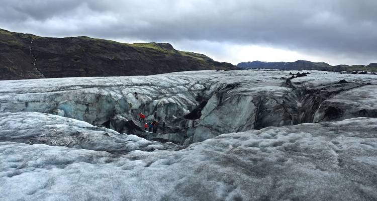 Personas explorando un vasto glaciar bajo un cielo nublado.
