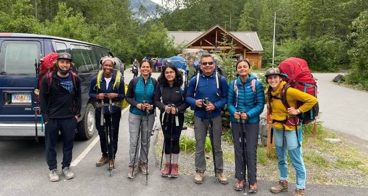 A group of hikers posing with gear in a parking lot.