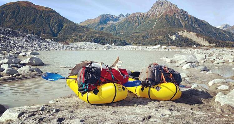 Two kayaks loaded with gear on a rocky shore.